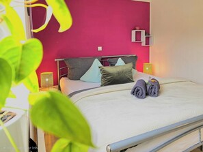 A hotel room with a bed, pillows, a bedside table with a lamp, and a wall-mounted shelf. - Hot Tub & View of the Dolomites on the Eifelsteig Trail (Gerolstein)