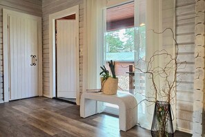 A room with a wooden floor, a bench with a woven basket, and a plant in a wire pot.