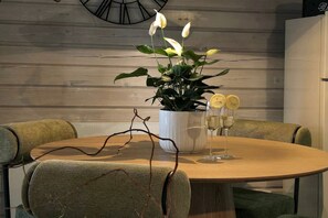 A dining table with a potted plant and two glasses of champagne.