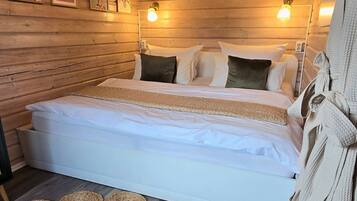 A wooden-paneled room with a bed, two wall-mounted lights, and a woven rug.