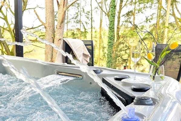 A hot tub with water jets, a towel, and a vase with flowers.
