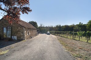 Ein Steingebäude mit einer Schotterauffahrt, die zu einem Weinberg führt.