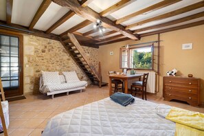 Une chambre à coucher comprenant un lit, un bureau, une commode, une chaise, une fenêtre et un escalier.
