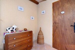 A wooden dresser with a cow figurine, a woven basket, and a wooden door with a metal handle. - Guesthouse “Chez Fayol” with Shared Pool, Communal Garden, and Wi-Fi (Montagnac-la-Crempse)