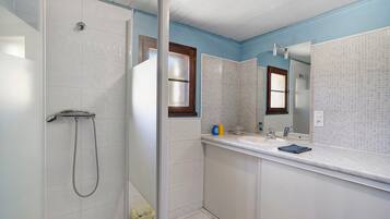 Ein Badezimmer mit Dusche, Waschbecken, Spiegel und Fenster.