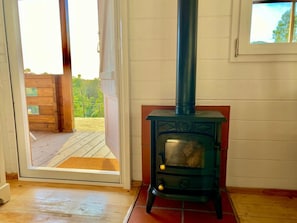 Una estufa de leña en una habitación con un ventanal corredero que da a un espacio exterior.