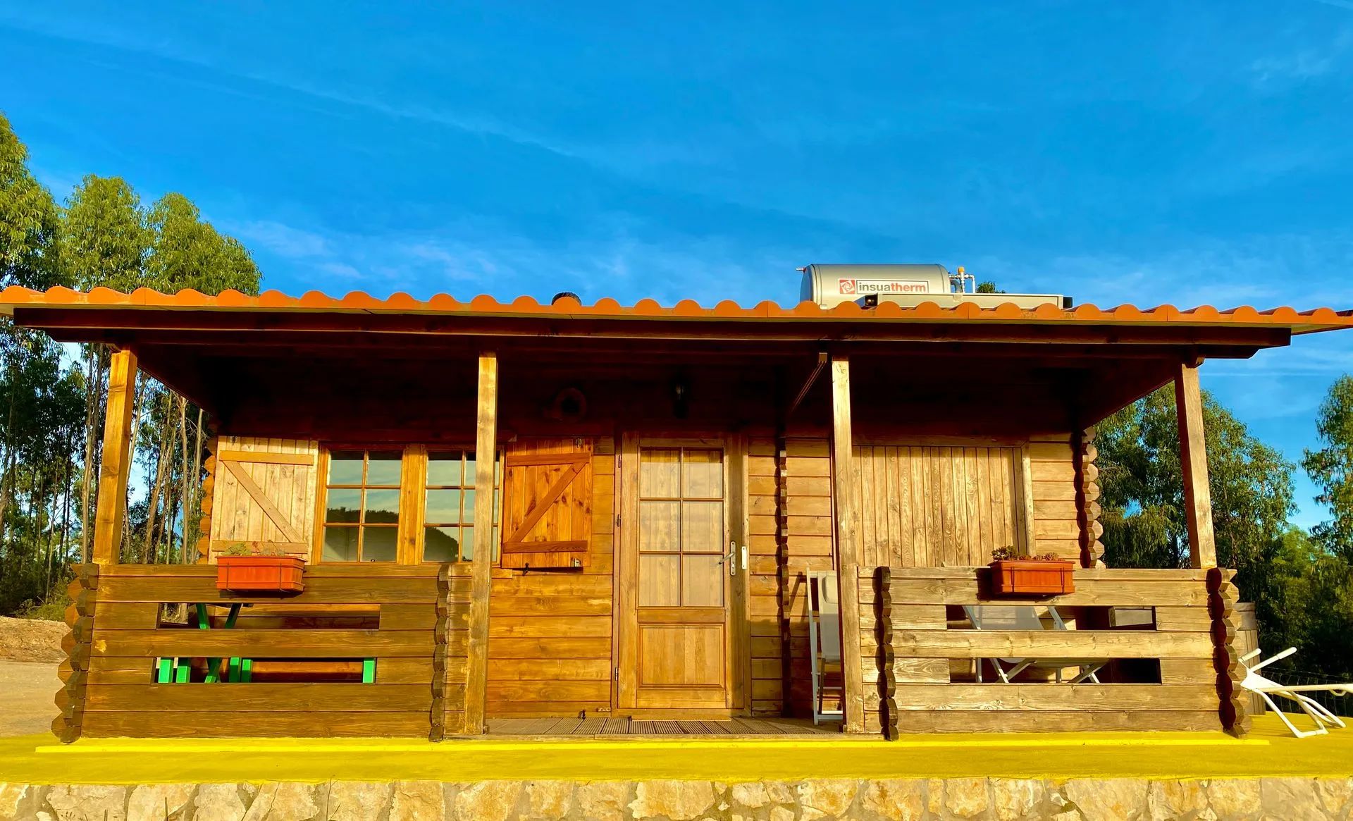 Eine Holzhütte mit Veranda, einer Tür und einem kleinen Anbau.