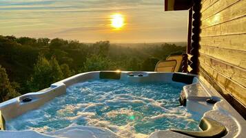 Uma banheira de hidromassagem com vista para o pôr do sol e árvores ao redor.