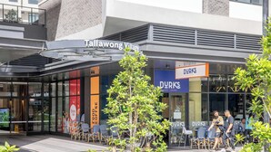 Ein Geschäft mit einem Schild für 'Tallahong Village' und 'DURK'S Cafe & Eatery' und Außenplätzen.