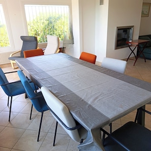 A conference room with a long table, several chairs, a television, and a window with blinds. - Charming house 900 meters from the ocean (Plouha)
