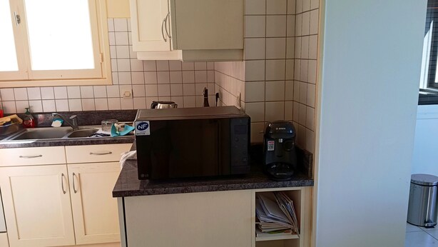 Uma cozinha com micro-ondas, torradeira e cafeteira na bancada.