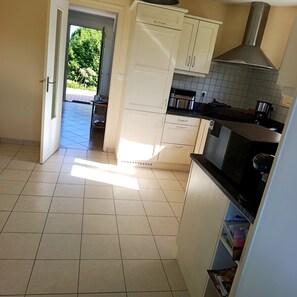 A kitchen with white cabinets, a black countertop, and a stainless steel range hood. - Charming house 900 meters from the ocean (Plouha)