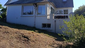 Uma casa de dois andares com telhado inclinado, chaminé e antena parabólica.