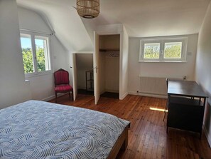 A bedroom with a bed, a chair, a radiator, and a window. - Charming house 900 meters from the ocean (Plouha)