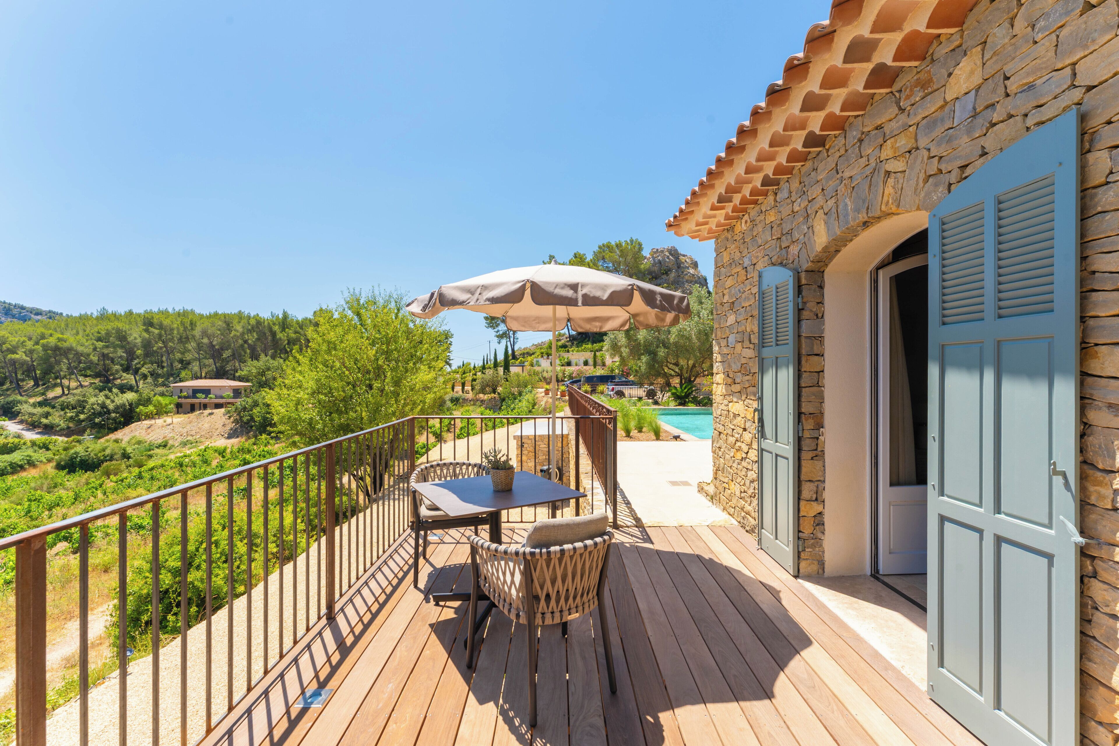 Une terrasse en bois avec des meubles d’extérieur, une table et un parasol.