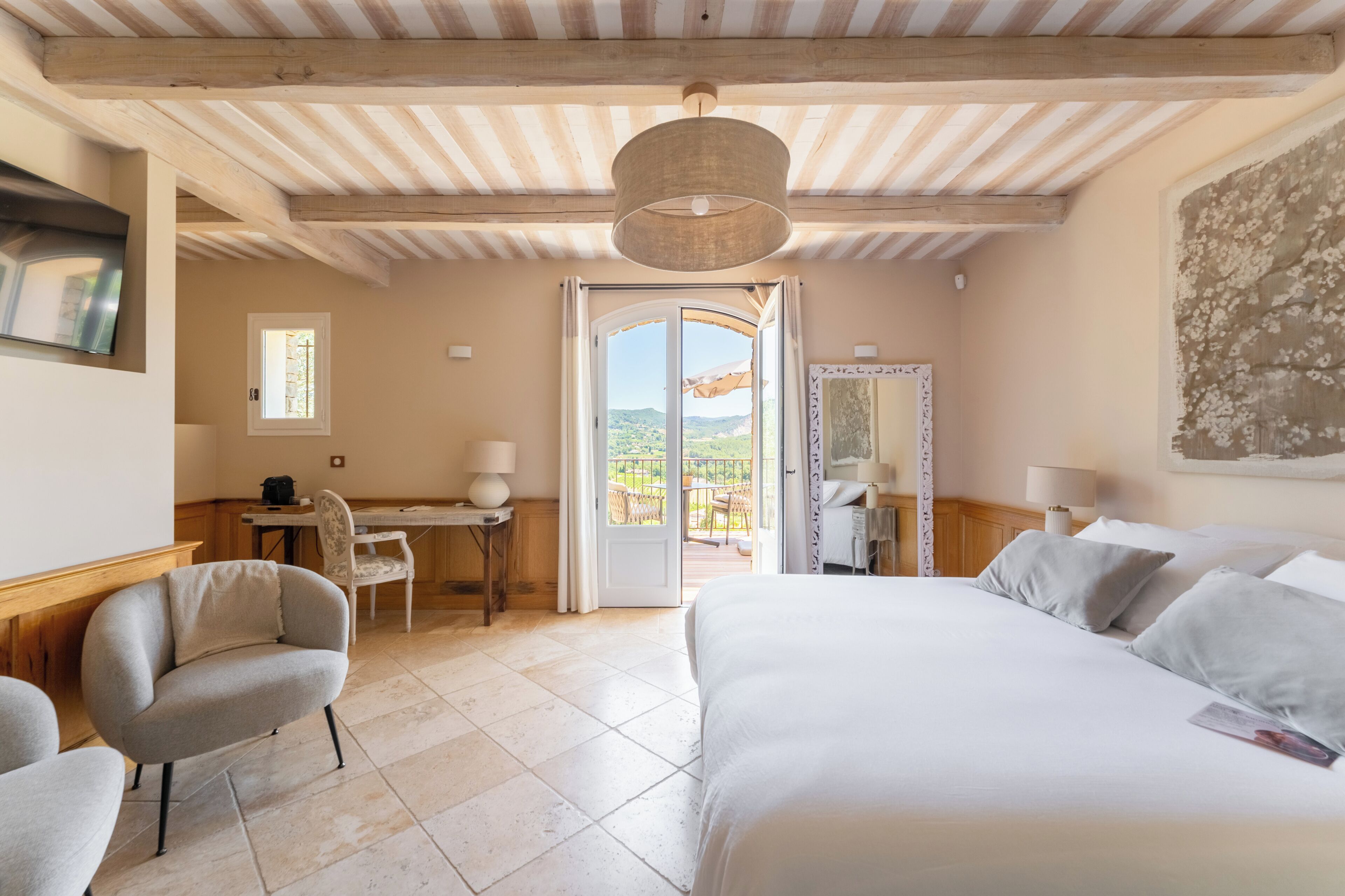 Habitación de hotel con cama, escritorio, silla y vistas al exterior.