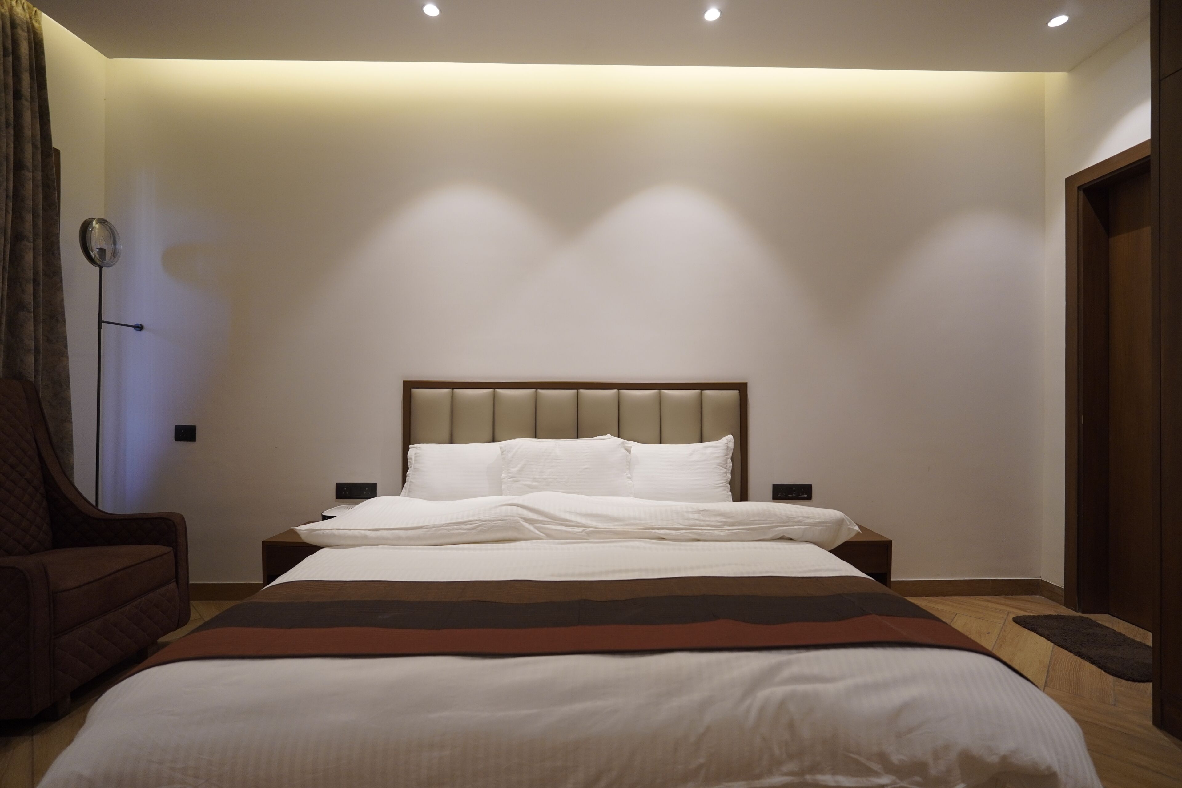 Un dormitorio con cama, una silla y una mesita de noche.