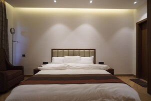 Un dormitorio con cama, una silla y una mesita de noche.