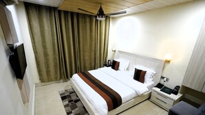 Una habitación de hotel con cama, mesita de noche, lámpara y ventilador de techo.