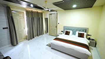 Habitación de hotel con cama, cortinas, ventilador de techo y piso de baldosas.