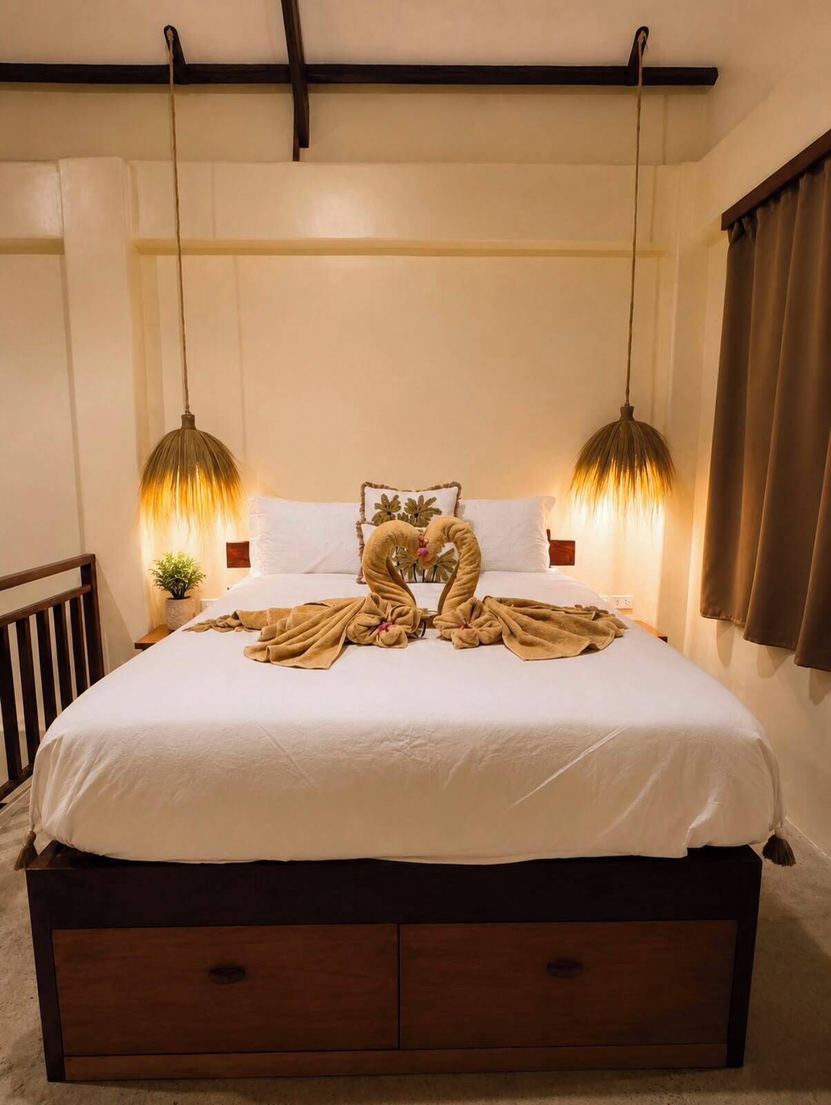 Una cama bien hecha con un arreglo de toallas simétrico, dos lámparas colgantes y un cabecero de madera.