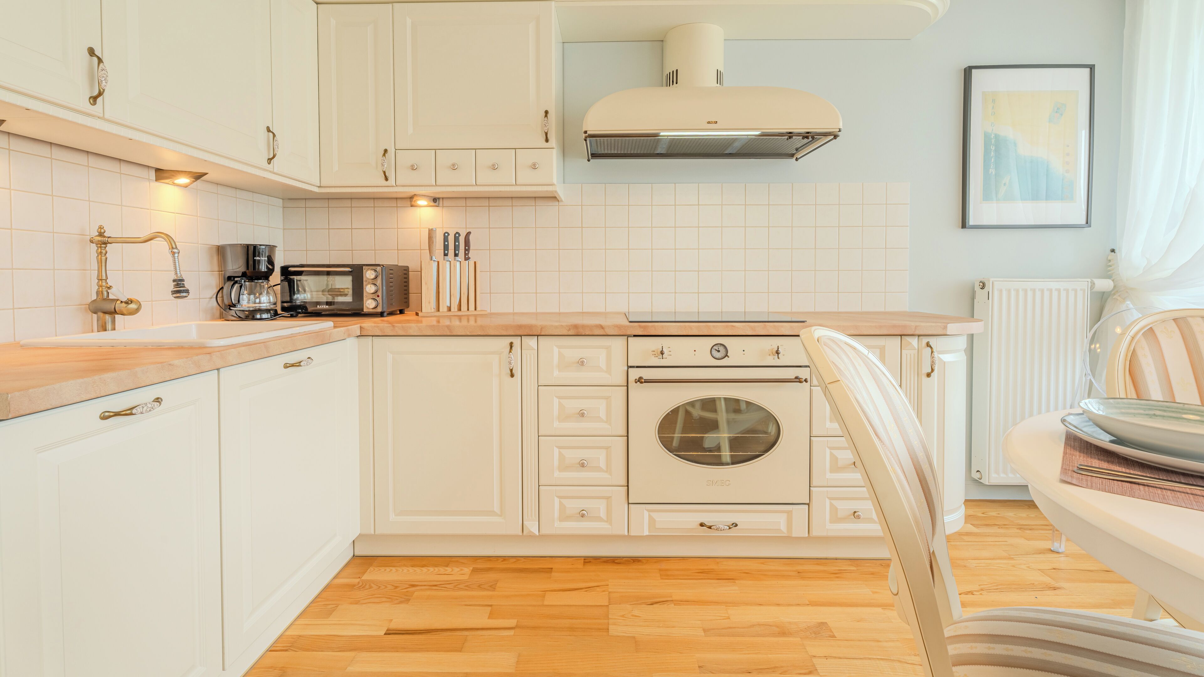 Een keuken met witte kasten, een ingebouwde oven, een koffiezetapparaat en een broodrooster.