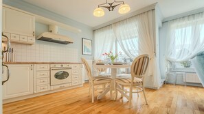 Une cuisine équipée d’un four encastré, de meubles en bois et d’un coin repas avec des chaises et une table.