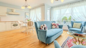 Ein modernes Wohnzimmer mit einem blauen Sofa, einem Essbereich und einer Küche.