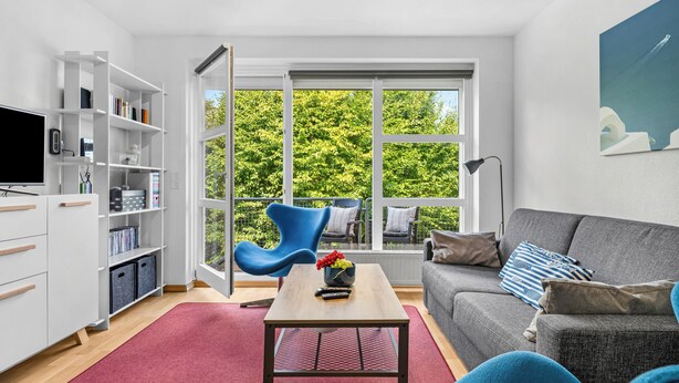 A modern living room with a grey sofa, a blue armchair, a wooden coffee table, and a bookshelf. - Buntfisch – A stunning maisonette flat just 300 metres from the Baltic Sea (Schönberg (Holstein))