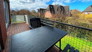 A balcony with a table and chairs, overlooking a garden and neighboring houses. - Buntfisch – A stunning maisonette flat just 300 metres from the Baltic Sea (Schönberg (Holstein))