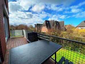 A balcony with a table and chairs, overlooking a garden and neighboring houses. - Buntfisch – A stunning maisonette flat just 300 metres from the Baltic Sea (Schönberg (Holstein))
