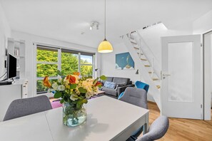 A modern living space with a dining area, a staircase, and a view of greenery outside. - Buntfisch – A stunning maisonette flat just 300 metres from the Baltic Sea (Schönberg (Holstein))