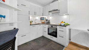 A modern kitchen with white cabinetry, a built-in oven, and a microwave. - Buntfisch – A stunning maisonette flat just 300 metres from the Baltic Sea (Schönberg (Holstein))