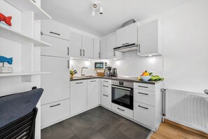 A modern kitchen with white cabinetry, a built-in oven, and a microwave. - Buntfisch – A stunning maisonette flat just 300 metres from the Baltic Sea (Schönberg (Holstein))