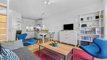 A modern living space with a kitchen, dining area, and a bookshelf.