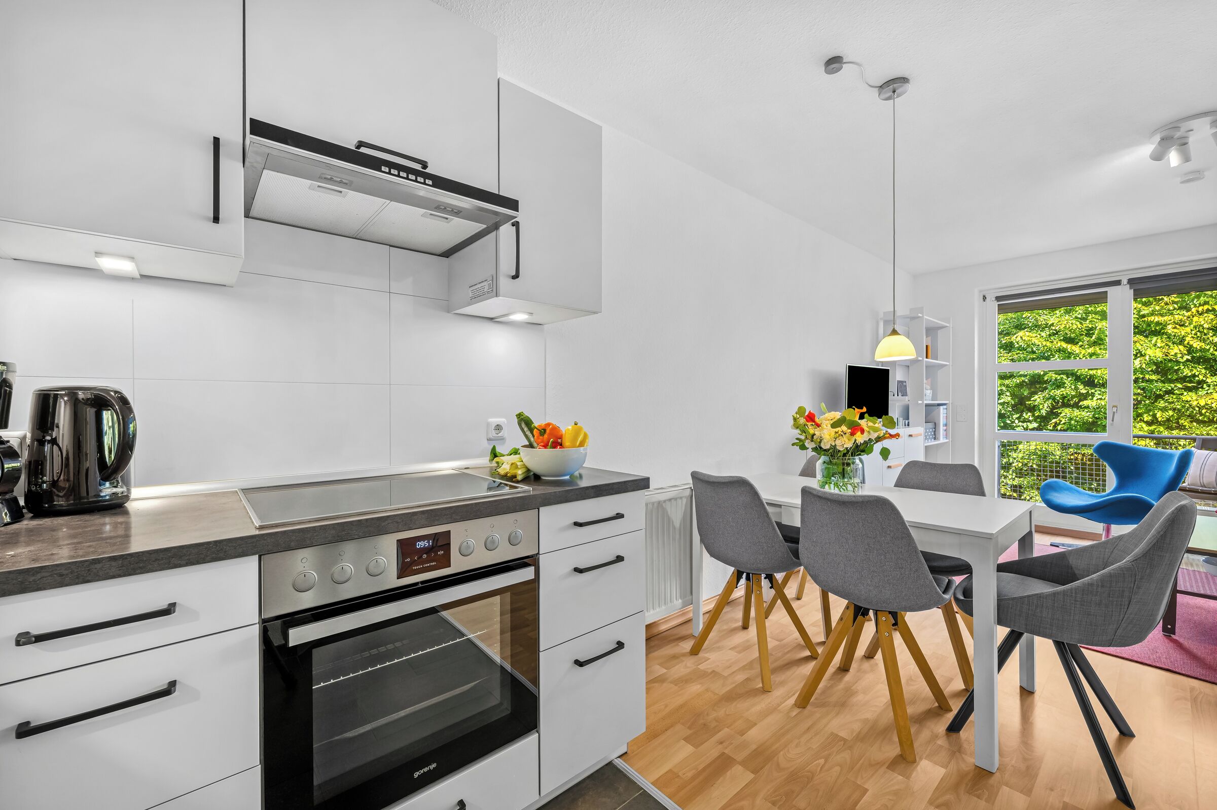 Eine moderne Küche mit Backofen, einer Kaffeemaschine und einem Essbereich mit Tisch und Stühlen.