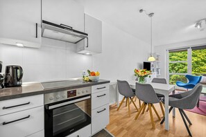 Eine moderne Küche mit Backofen, einer Kaffeemaschine und einem Essbereich mit Tisch und Stühlen.