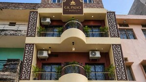 Un hotel con un cartel que dice 'G.K. Palace Hotel' y un letrero que anuncia comodidades como habitaciones con aire acondicionado, Wi-Fi gratuito, agua caliente, servicio 24 horas y un café en la azotea.
