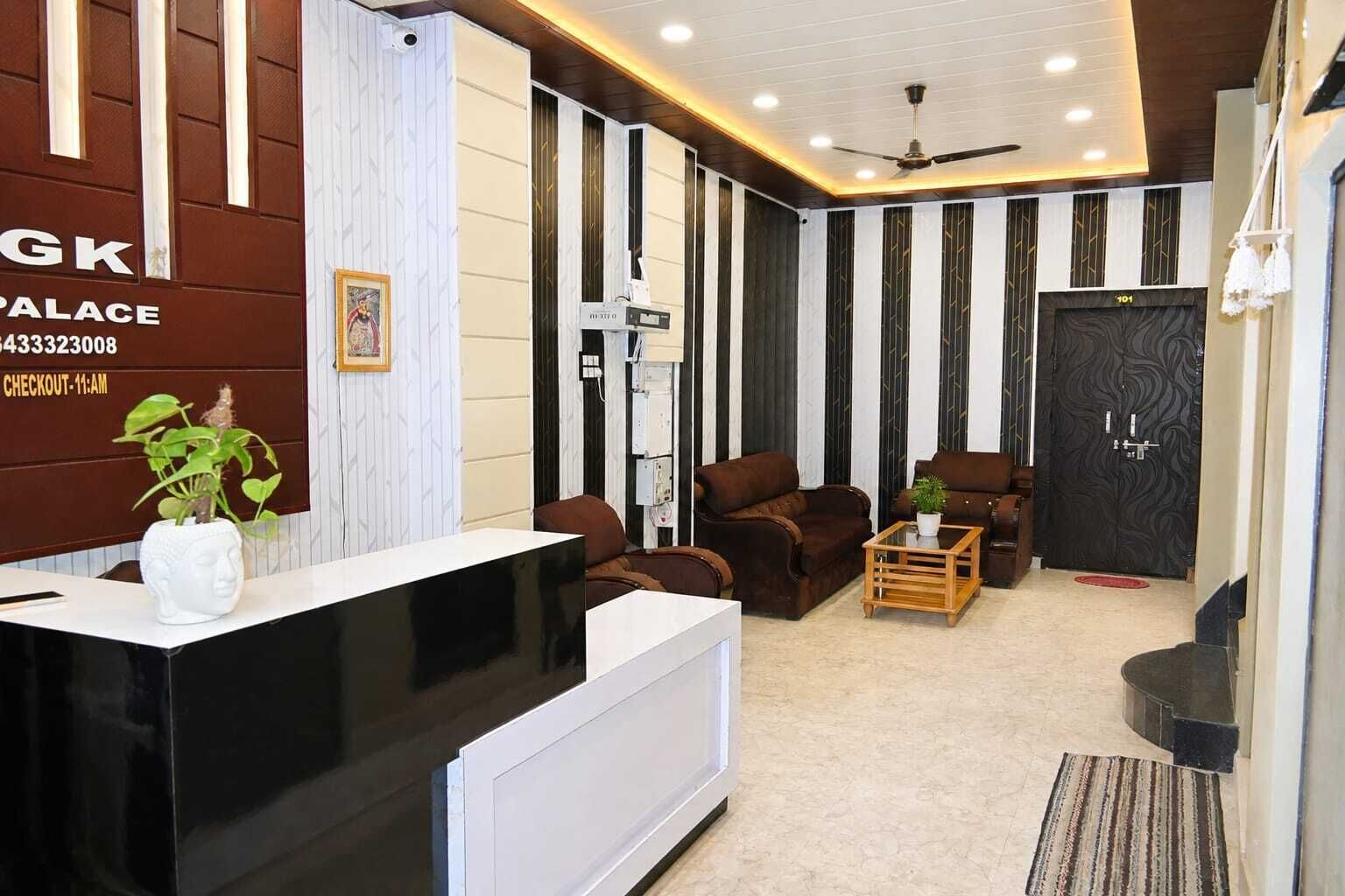 A hotel reception area with a black reception desk, a white vase with a plant, and two brown leather sofas.