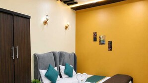 Una habitación de hotel con cama, armario, mesita de noche con planta y ventilador de techo.