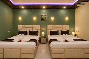 Habitación de hotel con dos camas, cada una con una toalla con forma de cisne y una mesita con lámpara.