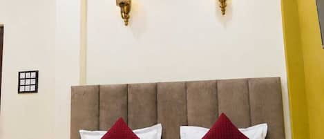 A hotel room with a bed, two wall sconces, a ceiling fan, and a decorative swan on the bed.