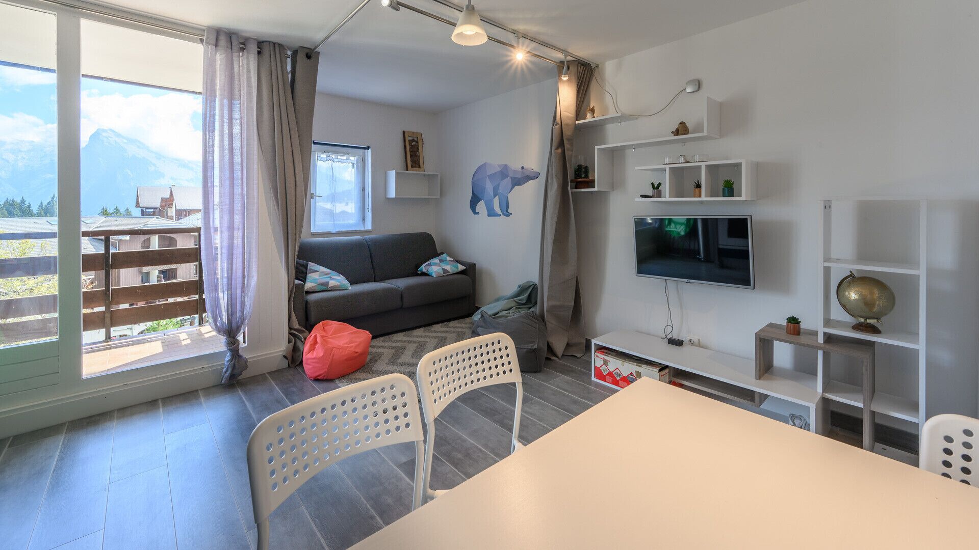 Uma sala de estar moderna com um sofá, uma TV e um espaço de jantar com cadeiras.