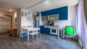 A compact kitchen with a dining area, a coffee machine, and a green chair. - Apartment with balcony and mountains view (Morillon)