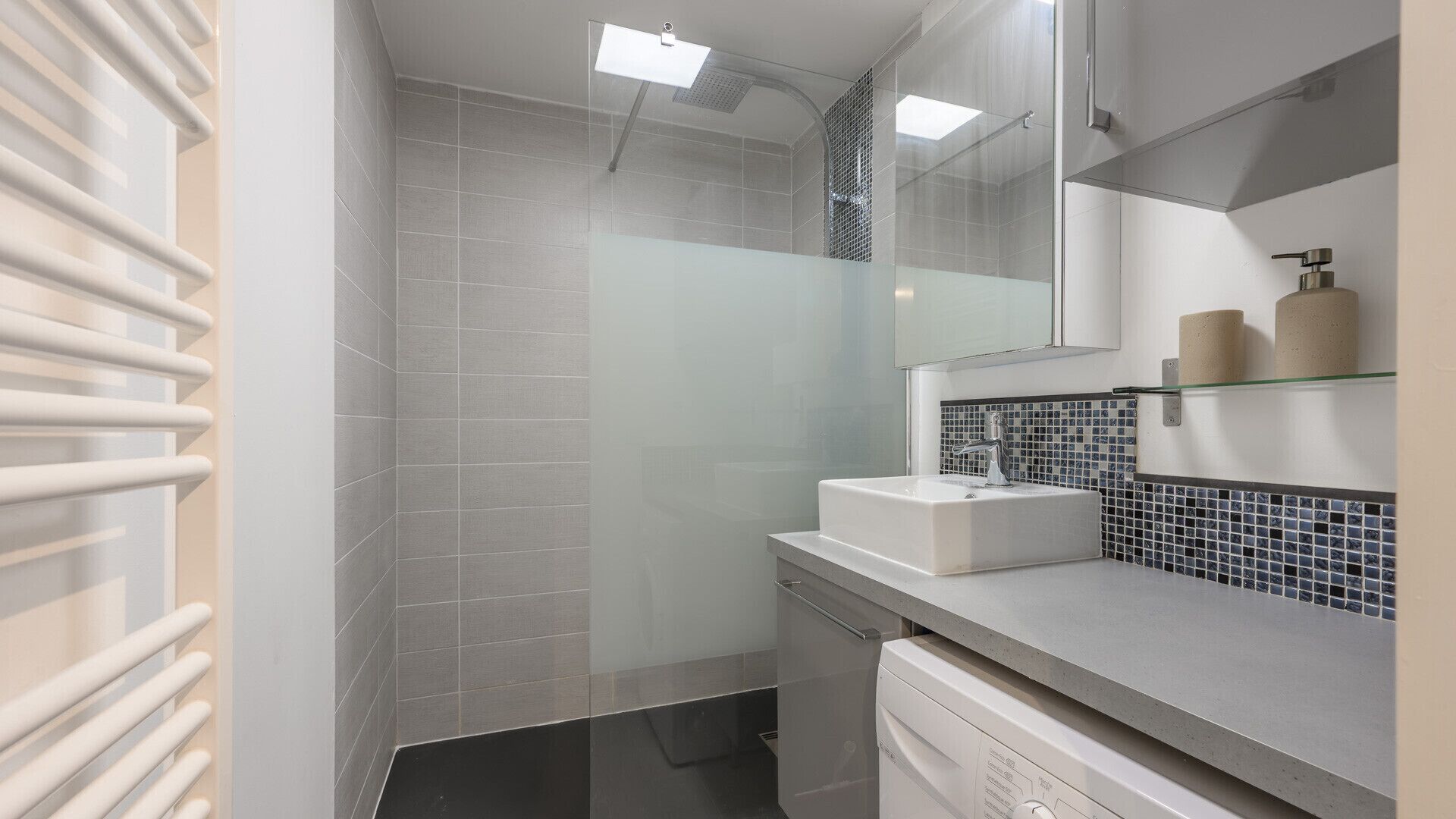 A modern bathroom with a shower, a sink, and a toilet.