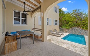 Ein überdachter Außenbereich mit Pool, Sitzgelegenheiten und Deckenventilator.