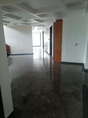 A hallway with a polished floor, white walls, and a wooden door. - The Jade Mountain by O9 Stay (Banikhet)