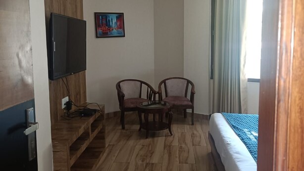 Habitación de hotel con cama, televisor, ventilador de techo y un cuadro en la pared.