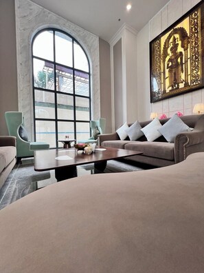 A modern living room with a large arched window, a sofa set, a coffee table, and a decorative wall piece. - Lavia Hotel (Phnom Penh)