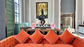 A modern interior with a sofa, a statue, and a dining area.